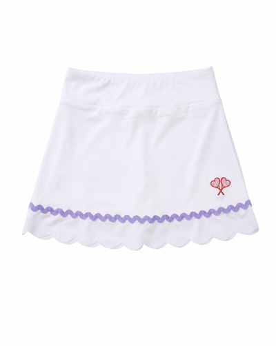 A white A-line skirt with a scalloped hem, a purple wavy trim, and a small red embroidered double-heart logo on the left hip, shown against a plain white background.