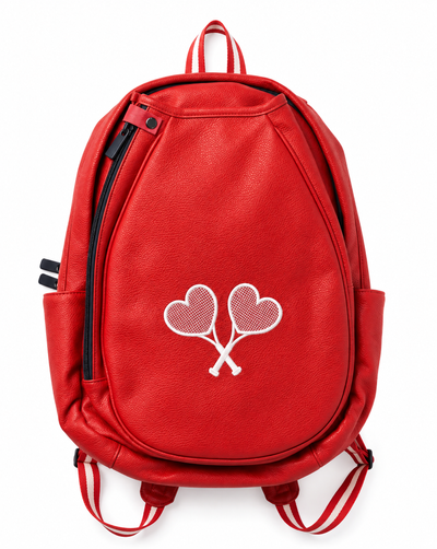 A red leather backpack with a white embroidered design of two heart-shaped tennis rackets crossed in the center, shown against a plain white background.